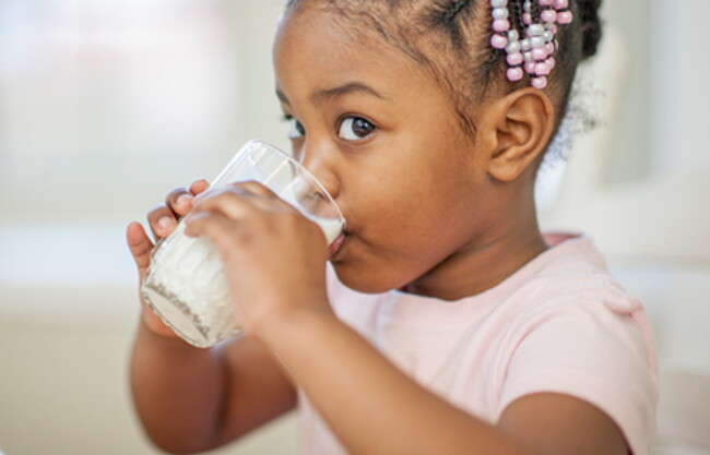 Essential iron-fortified cereals - a little girl drinking milk from a glass.