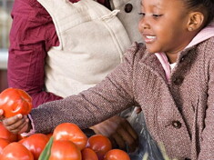 A girl helping her mom choosing fruits and vegetables.