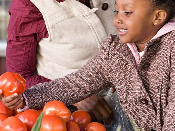 A girl helping her mom choosing fruits and vegetables.