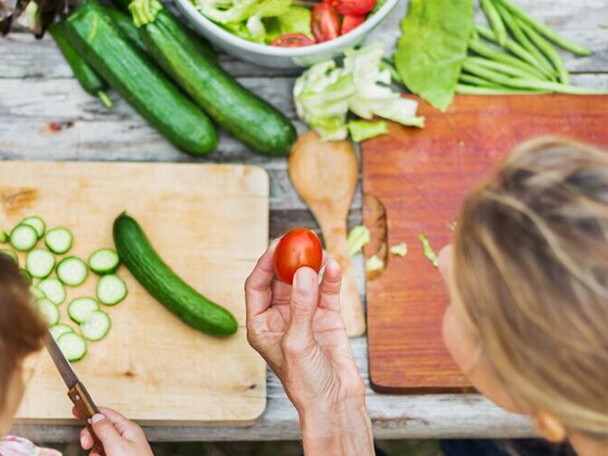 A woman teching a child to prepare vegetables.