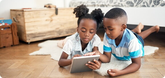 children lying on the floor playing on a tablet children lying on the floor playing on a tablet